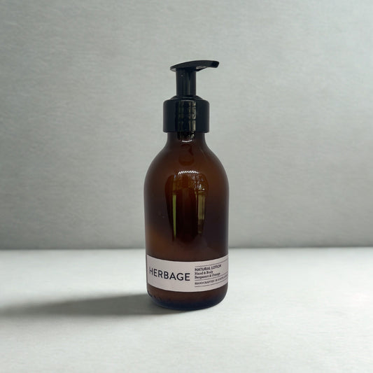 Brown bottle with pump and Herbage Natural Lotion on a light grey background