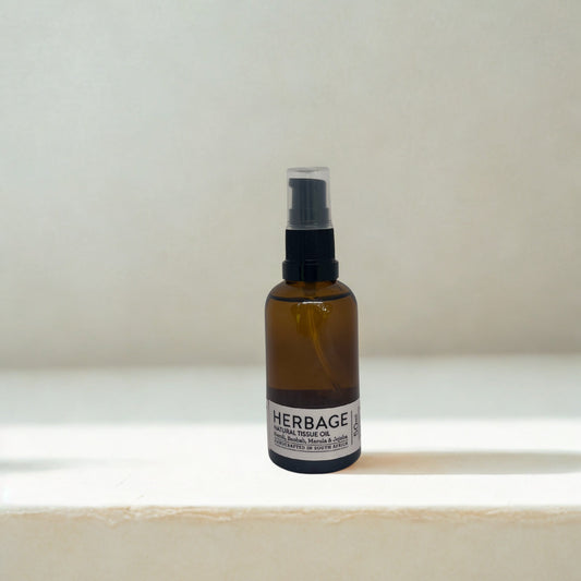 Brown bottle Herbage Natural Tissue Oil on a white surface with a light grey background