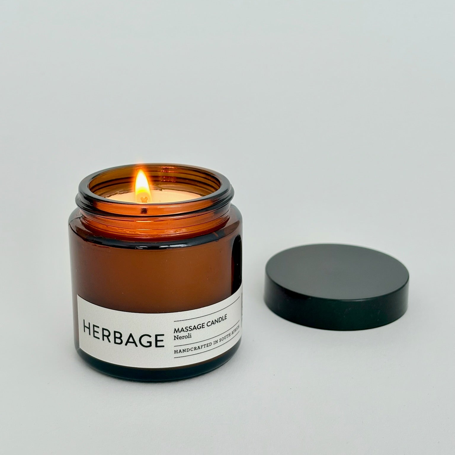 Amber candle in a glass jar with a visible label on a light gray background