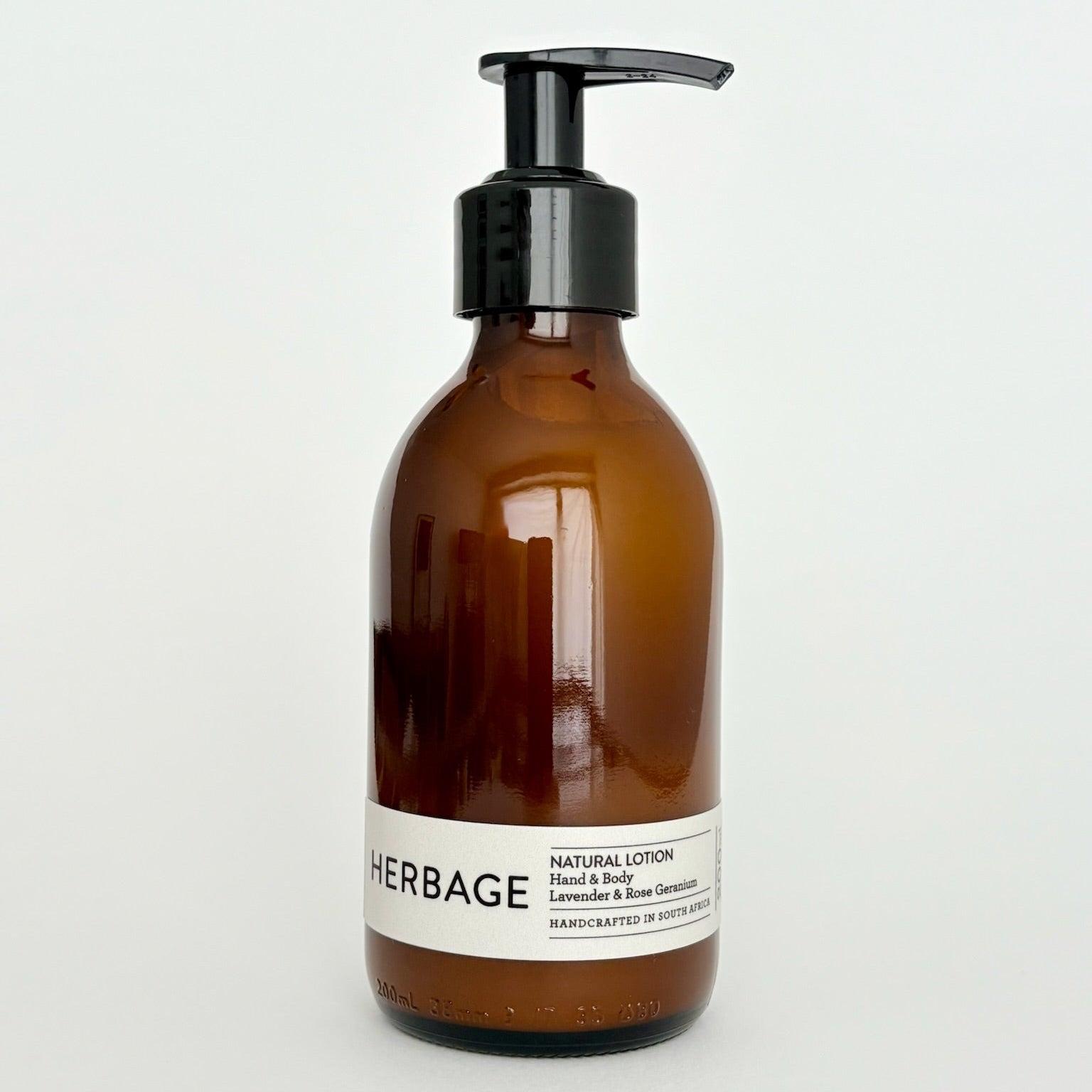 Brown lotion bottle with pump and white label on a light gray background