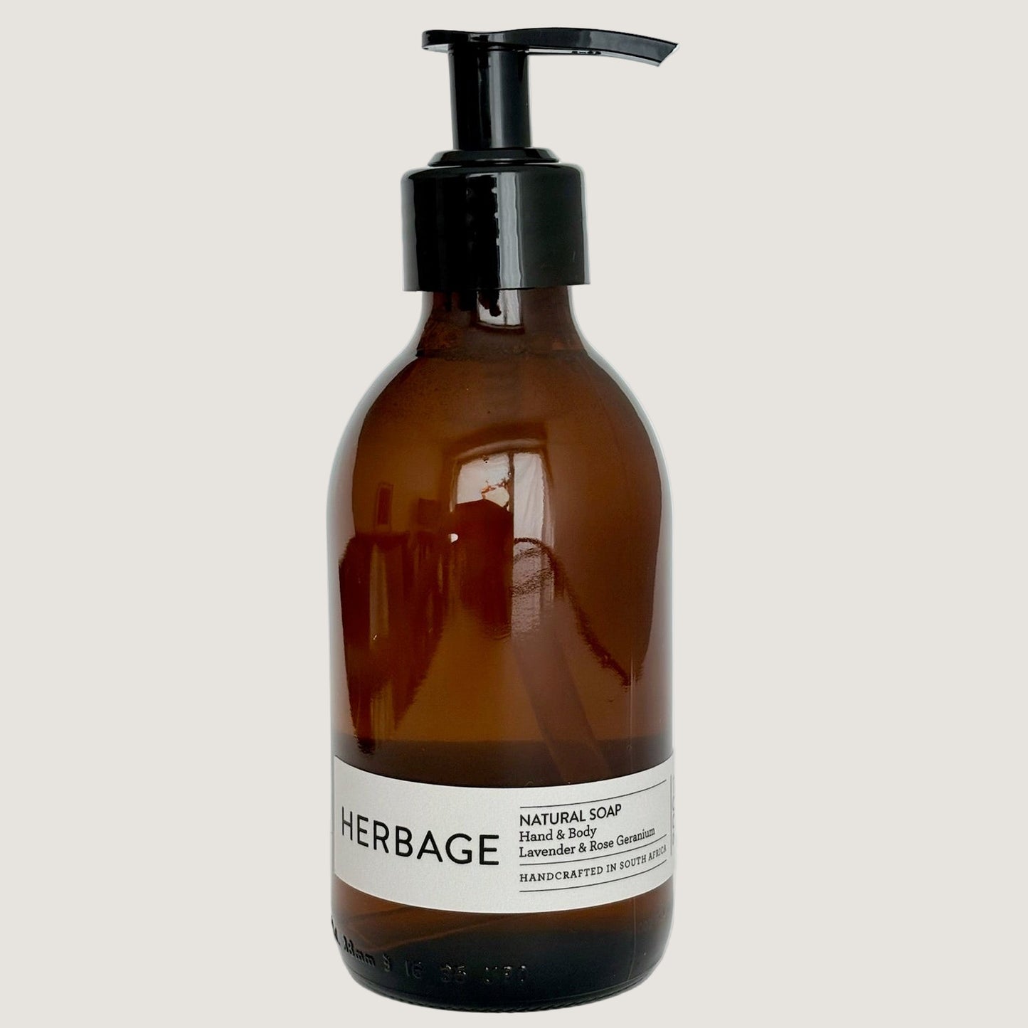 Brown bottle with black pump and white label on a light gray background